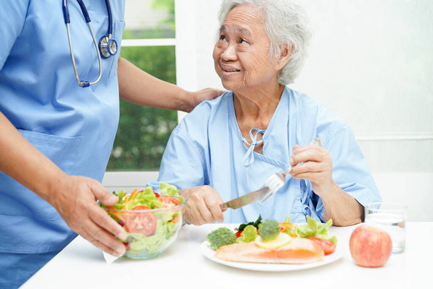 Asiatico anziana donna paziente mangiare salmone paletto e verdura insalata per sano cibo in ospedale. - Foto, immagini