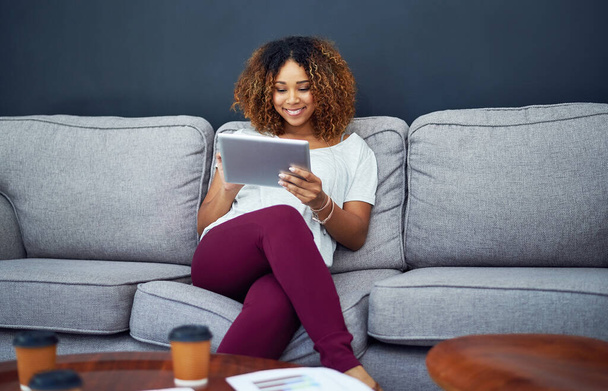 Pohodlnost inspiruje její produktivitu. mladá podnikatelka používající digitální tablet na pohovce v moderní kanceláři - Fotografie, Obrázek