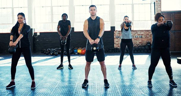 Manter-se forte e em forma. um grupo de fitness usando kettle-sinos em sua sessão no ginásio - Foto, Imagem