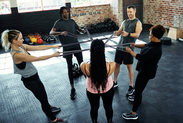 Mit der richtigen Unterstützung kann man so weit kommen. eine Fitnessgruppe, die im Fitnessstudio mit Widerstandsbändern trainiert - Foto, Bild