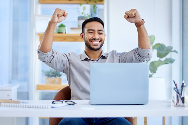 Businessman, laptop and celebrate success or win at desk with fist for bonus deal. Excited Asian man or entrepreneur with tech for profit, competition or online achievement and loan notification. - Photo, image