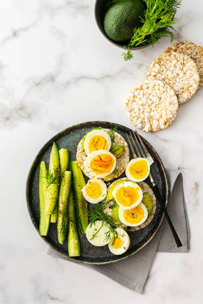 Healthy breakfasts, rice cakes with avocado and boiled eggs with dill and cucumber with spices, healthy wholesome food, top view - Foto, imagen