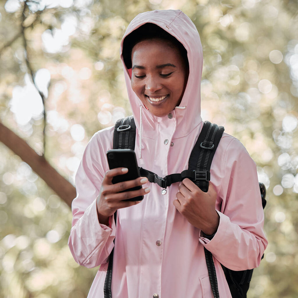 Black woman, phone and smile for hiking communication, social media or chatting in nature. Happy African female person or hiker smiling on mobile smartphone for trekking, travel or online location. - 写真・画像