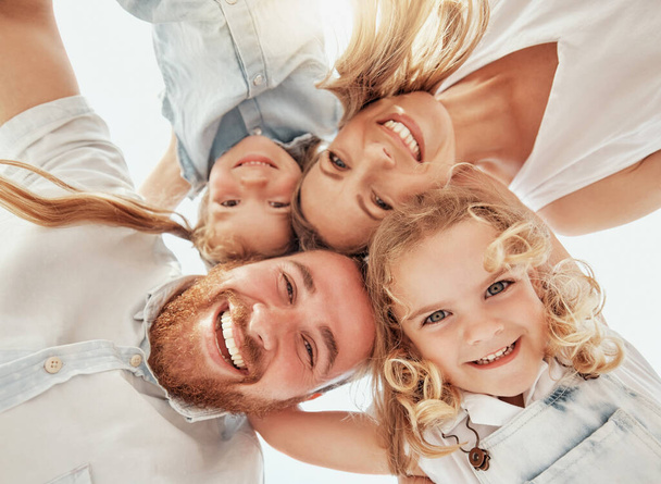Family portrait, heads together in circle from below and happiness, bonding and holiday travel to Australia. Face of mother, father and children with smile, happy outdoor huddle on summer vacation - Photo, Image