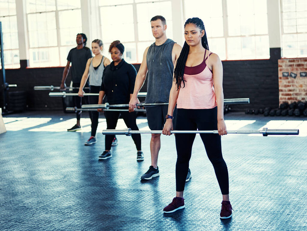 Faites de l'exercice une partie de votre routine quotidienne. un groupe de fitness utilisant des barres d'acier dans leur séance à la salle de gym - Photo, image