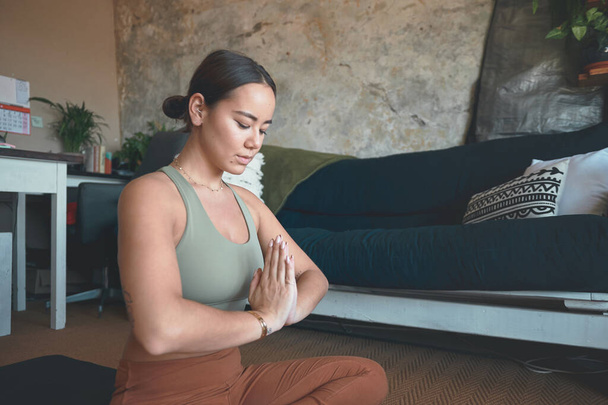 Déplacez votre attention vers l'intérieur pendant un moment. une jeune femme méditant tout en pratiquant le yoga à la maison - Photo, image