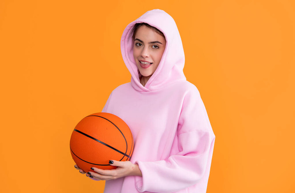 cheerful sporty girl with basketball ball on yellow background. - Фото, зображення