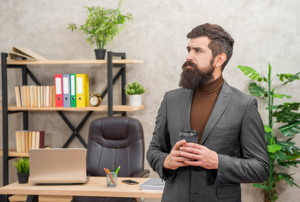 pondering brutal ceo in businesslike suit hold morning coffee cup at the office, to go. - Photo, image