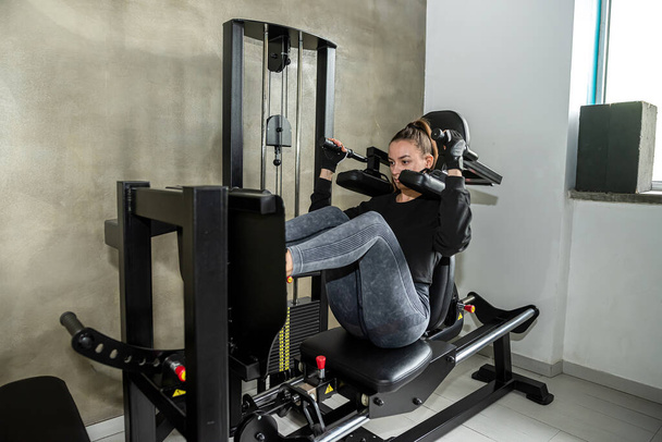 Attractive young woman doing exercises with a machine in the gym. the concept of losing excess weight. sport - Φωτογραφία, εικόνα