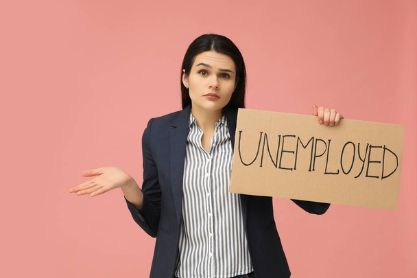 Unhappy woman holding sign with word Unemployed on pink background - Фото, зображення