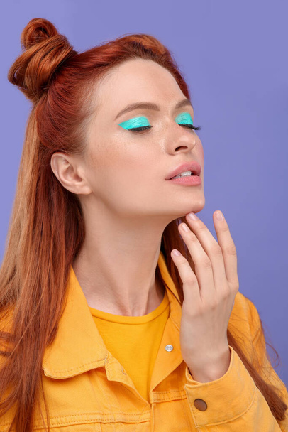 Beautiful woman with bright makeup and closed eyes posing on violet background - Фото, зображення