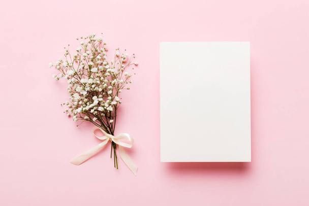 Wedding mockup with white paper list and flowers gypsophila on colored table top view flat lay. Blank greeting cards and envelopes. Beautiful floral pattern. Flat lay style. - Photo, Image
