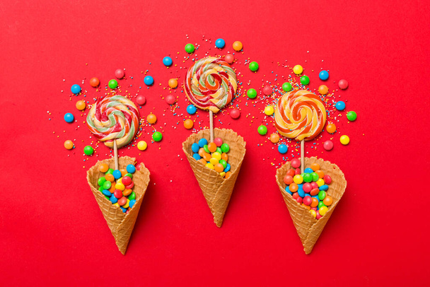 waffle cone full of assorted traditional candies falling out on colored background with copy space. Happy Holidays sale concept. - Zdjęcie, obraz