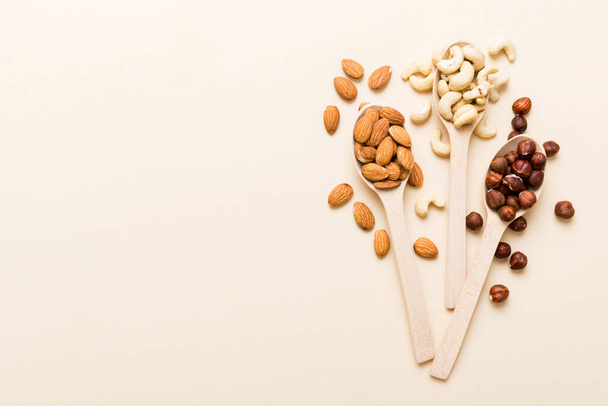 Assortment of nuts in wooden spoon on colored table. Cashew, hazelnuts, walnuts, almonds. Mix of nuts Top view with copy space. - Foto, Imagem