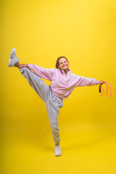 Krásná sportovkyně s skákacím lanem izolované na žlutém studiu - Fotografie, Obrázek
