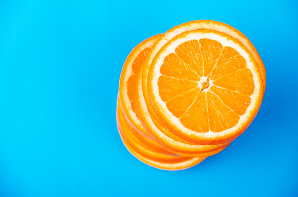 mavi bir arka plan üzerine dilimlenmiş portakal yığını - Fotoğraf, Görsel