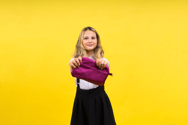 Little teenager girl with pencil case on a yellow background - Photo, Image