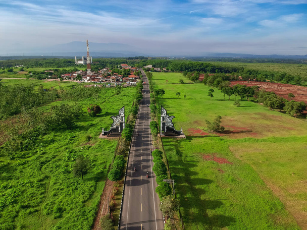 Vista aérea de la puerta fronteriza en Purwakarta. Vista del dron de caminos de asfalto con puertas tradicionales y plantaciones verdes.  - Foto, Imagen
