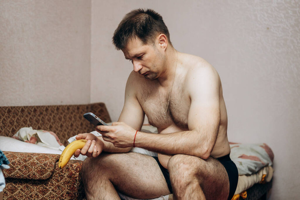 Guy without clothes holds a missing banana in his hand. Erection problem, male health - Foto, afbeelding