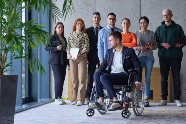 Diverse group of business people, including a businessman in a wheelchair in a modern office.  - Foto, Bild