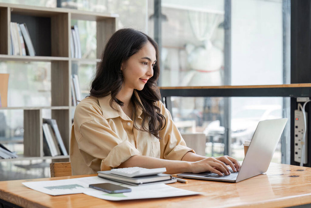 ビジネスの若い女性幸せな陽気なかわいいビジネスの女性は、ラップトップコンピュータを使用してオフィスに座る. - 写真・画像