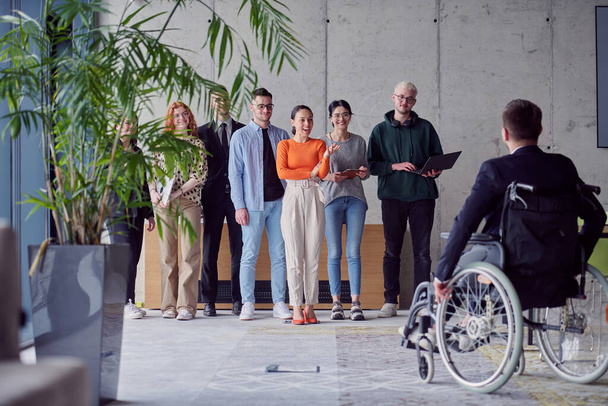 A group of diverse entrepreneurs gather in a modern office to discuss business ideas and strategies, while a colleague in a wheelchair joins them - Foto, afbeelding
