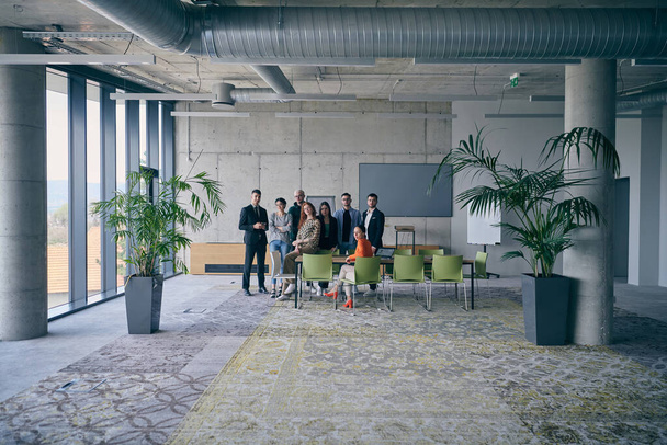 A diverse group of successful businesspeople gather and pose for a photo, showcasing teamwork and professional empowerment in a modern office setting - Foto, afbeelding