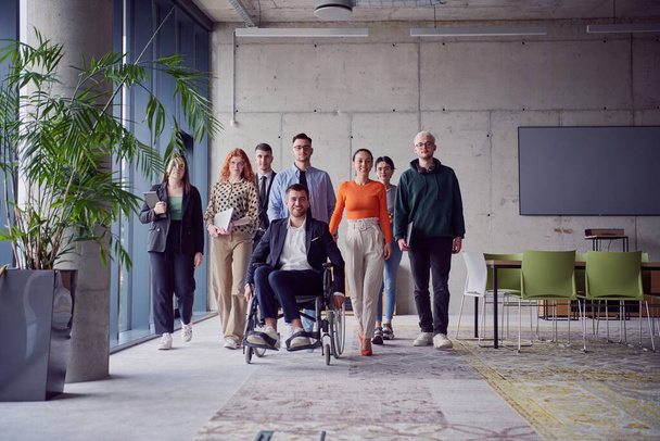 A diverse group of businessmen, including a businessman in wheelchair, confidently stride together through a modern, spacious office, epitomizing collaboration, inclusivity, and strength in unity.  - Foto, imagen