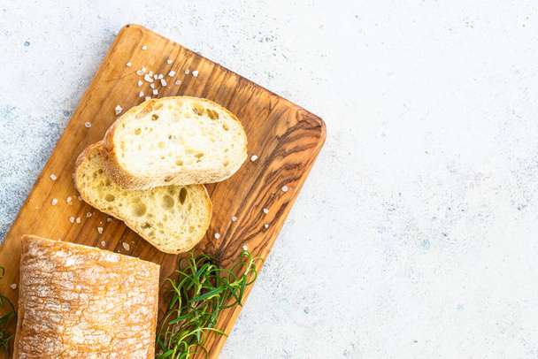 Italienisches Ciabatta-Brot auf Holzbrett. Draufsicht mit Kopierraum auf weißem Tisch. - Foto, Bild