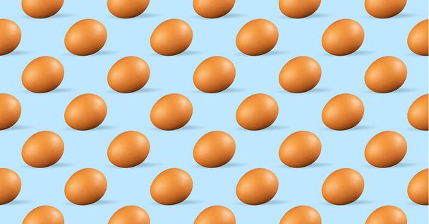 Seamless pattern of chicken eggs on blue background. Fresh repeating chicken eggs on blue background - 写真・画像