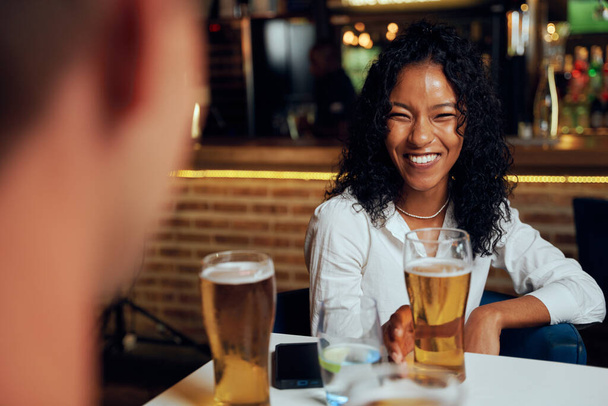 Young multiracial friends wearing casual clothing smiling while enjoying beers at restaurant - Fotoğraf, Görsel