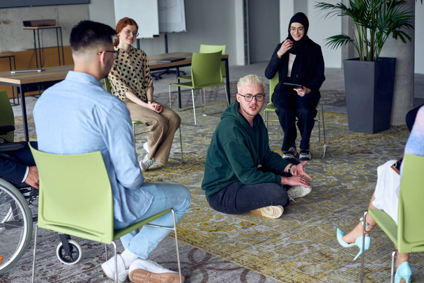 A man sitting at the center of a circle, passionately sharing his business ideas with his colleagues, fostering an atmosphere of collaboration and innovation in a dynamic and engaging workplace - Foto, afbeelding
