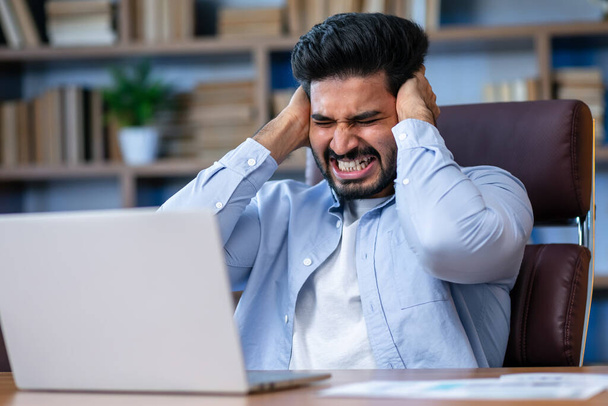 Arabischer Angestellter fühlt sich gestresst und ernst bei der Arbeit, während er im Büro mit Laptop arbeitet. - Foto, Bild