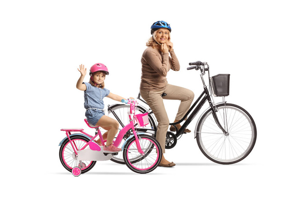 Mädchen und eine Frau auf Fahrrädern tragen Helme isoliert auf weißem Hintergrund - Foto, Bild