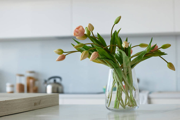 Крупним планом красиві квіти у скляній вазі, що стоїть на столі на вітчизняній кухні
 - Фото, зображення