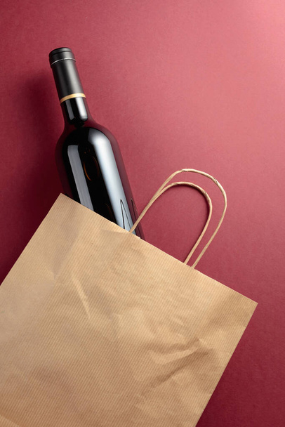 Recycled paper shopping bag with a bottle of red wine. Top view, copy space. - Φωτογραφία, εικόνα