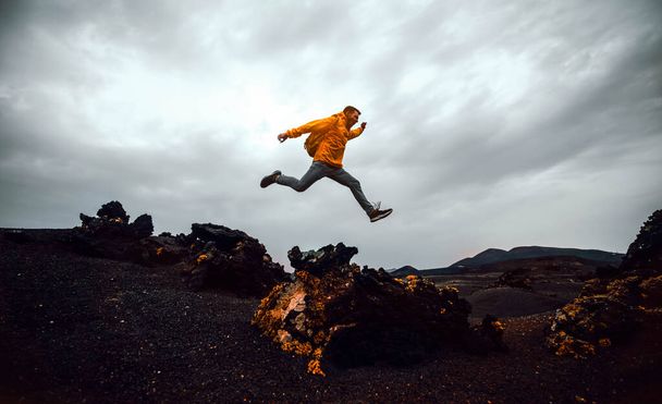 ハイカーの男は曇りの日に山を飛び越える。自由、リスク、成功と挑戦。男に集中しろ - 写真・画像
