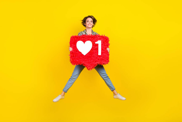 Full length photo of cool pretty lady wear animal print shirt rising heart pinata jumping high isolated yellow color background. - Foto, afbeelding