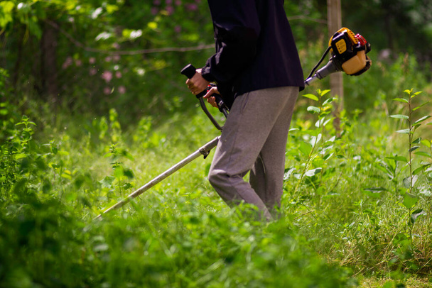Kaukasische tuinman werkende man Handmatig grasmaaier Wiet snijder of Power Weeder of Brush Cutter Lawn Mowe Benzine close-up - Foto, afbeelding