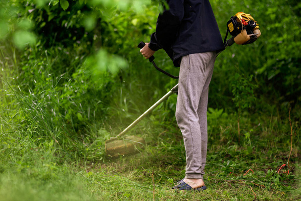 Kaukaski ogrodnik pracujący człowiek Ręczny kosiarka do trawy Weed Cutter lub Power Weeder lub Brush Cutter Trawnik Mowe Gasoline zbliżenie - Zdjęcie, obraz