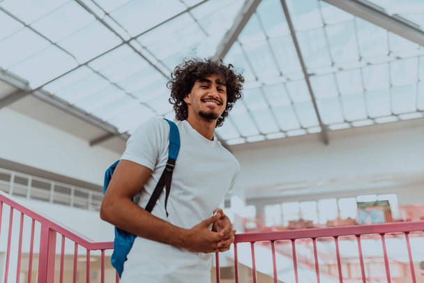 An Afro-American student with a blue backpack, sporting a modern Afro hairstyle and a wide smile, radiates enthusiasm and represents the vibrant spirit of a modern university, embodying ambition - Foto, imagen