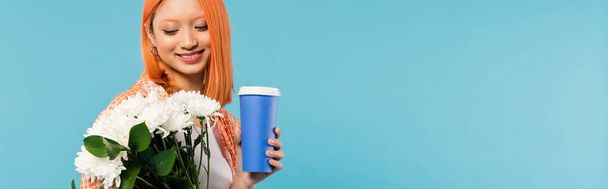 весенние вибрации, счастливая азиатская и молодая женщина с рыжими волосами держа бумажную чашку и букет цветов на голубом фоне, случайный наряд, поколение z, культура кофе, кофе на вынос, баннер  - Фото, изображение