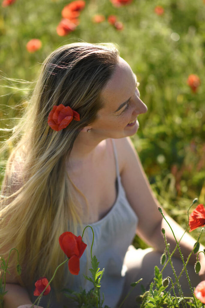 happy woman in a poppy flower field on summer sunny day.  - Фото, зображення