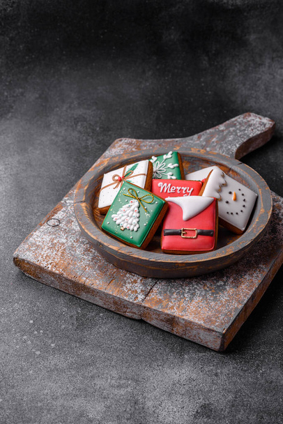 Mooie gekleurde kerst peperkoek koekjes voor het ontwerp en de decoratie van de feestelijke tafel op een getextureerde betonnen achtergrond - Foto, afbeelding