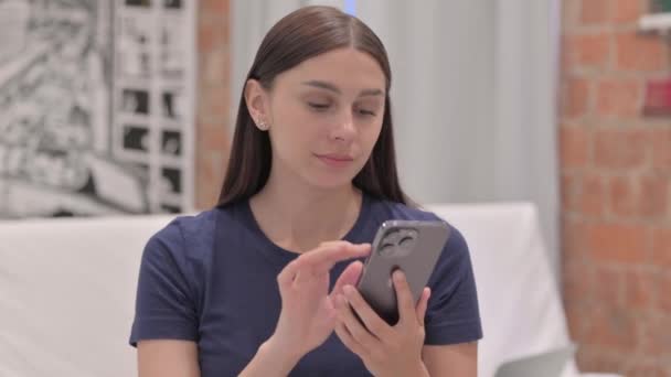 Nuoren latinonaisen muotokuva nainen juhlii menestystä älypuhelimessa - Materiaali, video