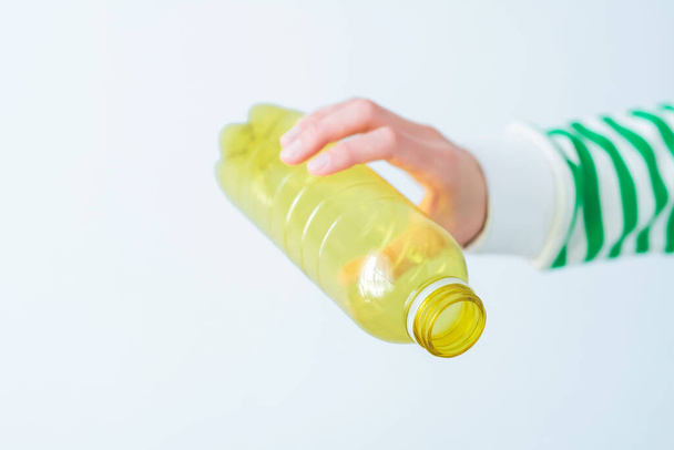 Seleção, eliminação e reciclagem de plástico. Uma mão feminina segurando uma garrafa de bebida plástica vazia em um fundo cinza. Foto de alta qualidade - Foto, Imagem