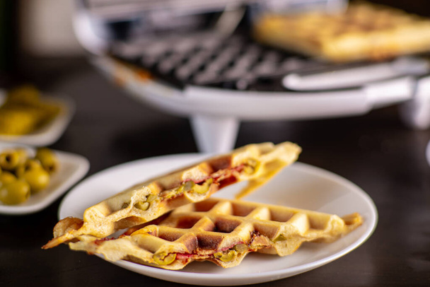 Pizza waffles, piffle. Waffles stuffed with sausage, cheese, tomatoes on a plate. - Photo, Image
