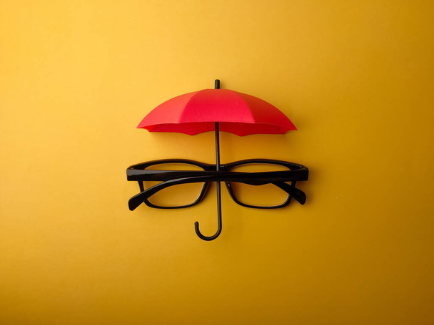 Um die Brille mit rotem Schirm auf gelbem Hintergrund zu betrachten - Foto, Bild