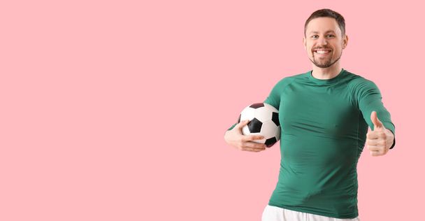 Hombre feliz con pelota de fútbol mostrando el pulgar hacia arriba sobre fondo rosa con espacio para el texto - Foto, imagen