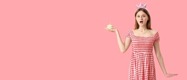 Surprised young woman with birthday cake on pink background with space for text - Photo, Image